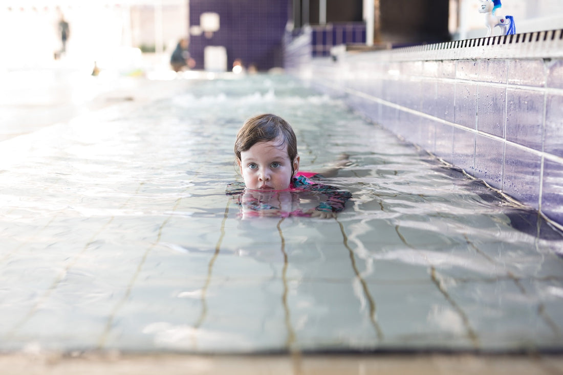 A little girl plays in the shallow end of the pool
