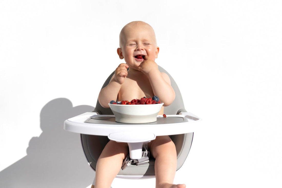 A baby eats a bowl of berries