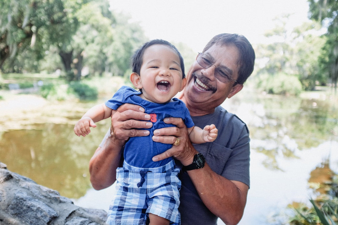 A happy grandfather holds his toddler son
