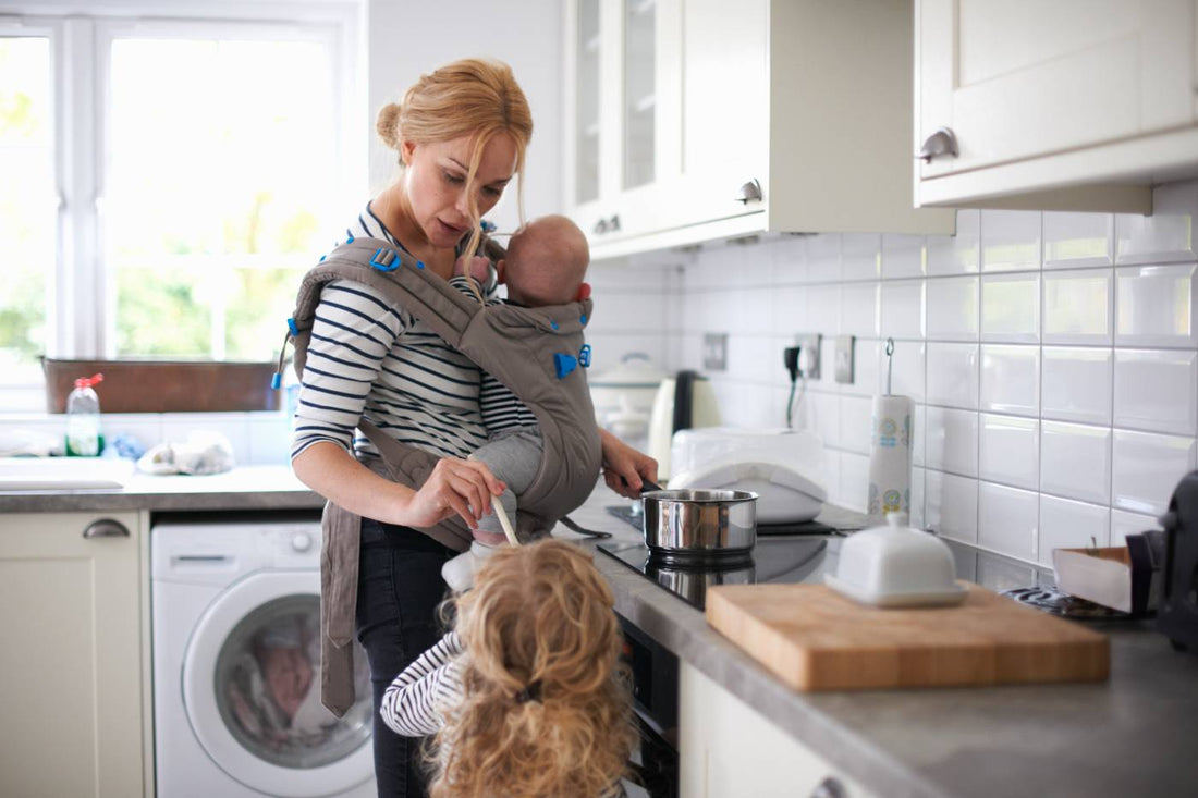 mum juggling two kids in kitchen carrying the mental load of parenthood