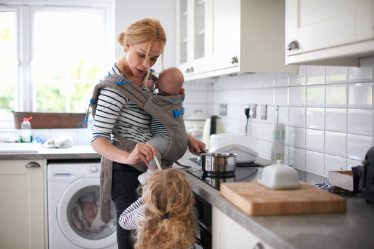mum juggling two kids in kitchen carrying the mental load of parenthood