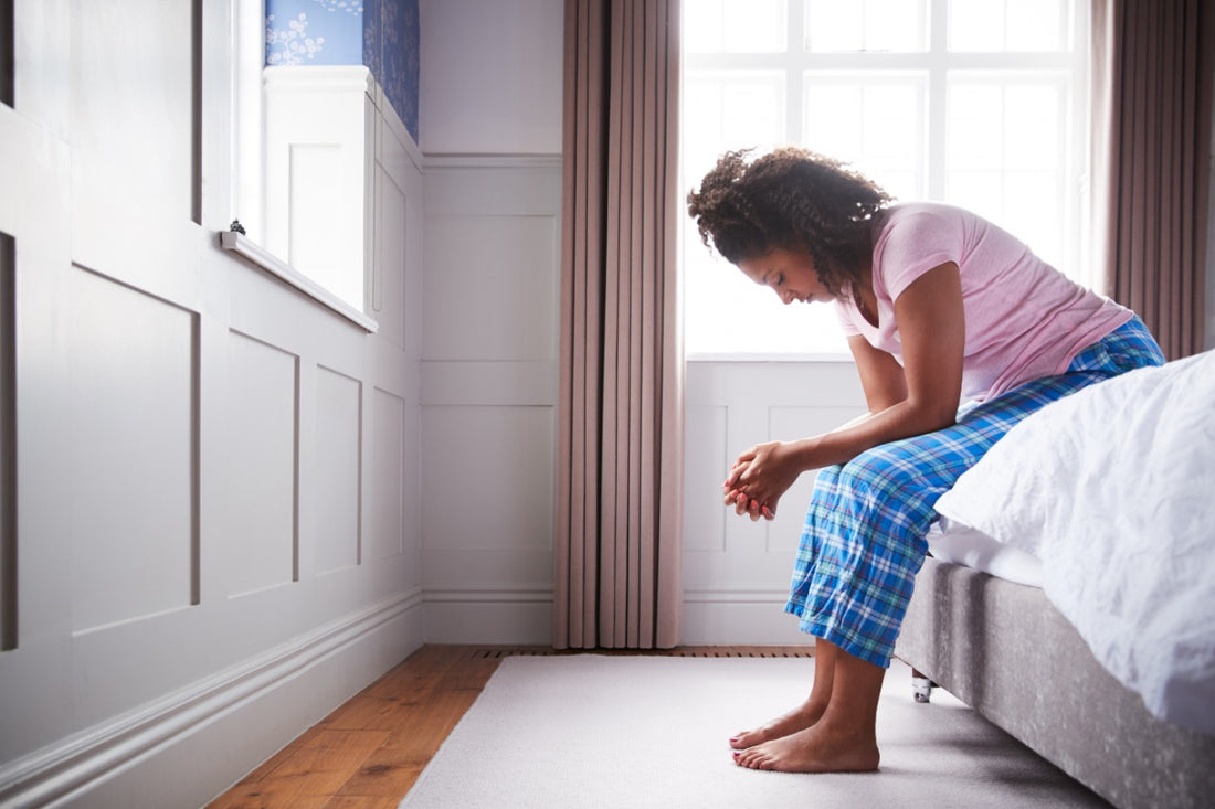 pregnant woman with morning sickness sitting on bed with