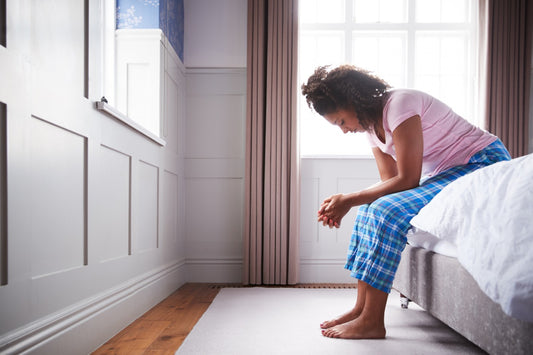 pregnant woman with morning sickness sitting on bed with
