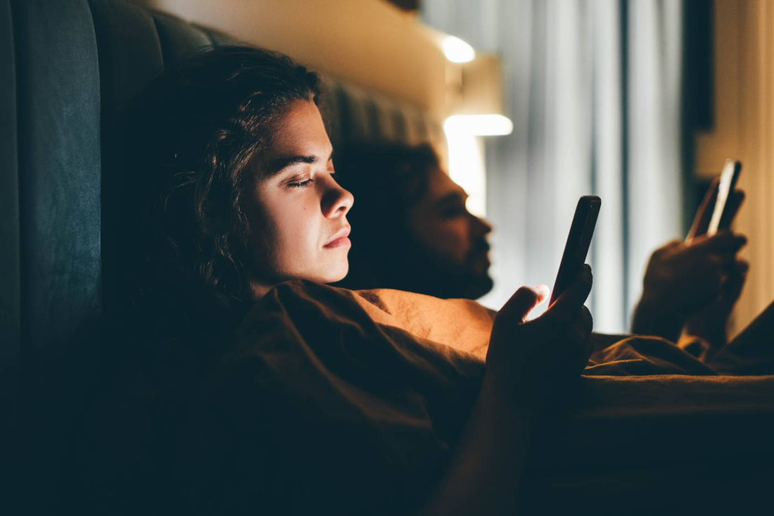 couple in bed looking at phones due to revenge bedtime procrastination