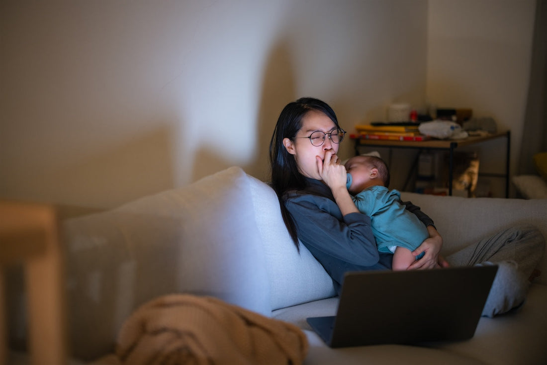 Tired mum holds newborn at night