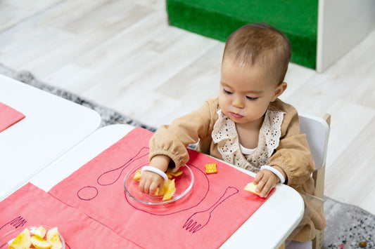 A toddler eats at a small table