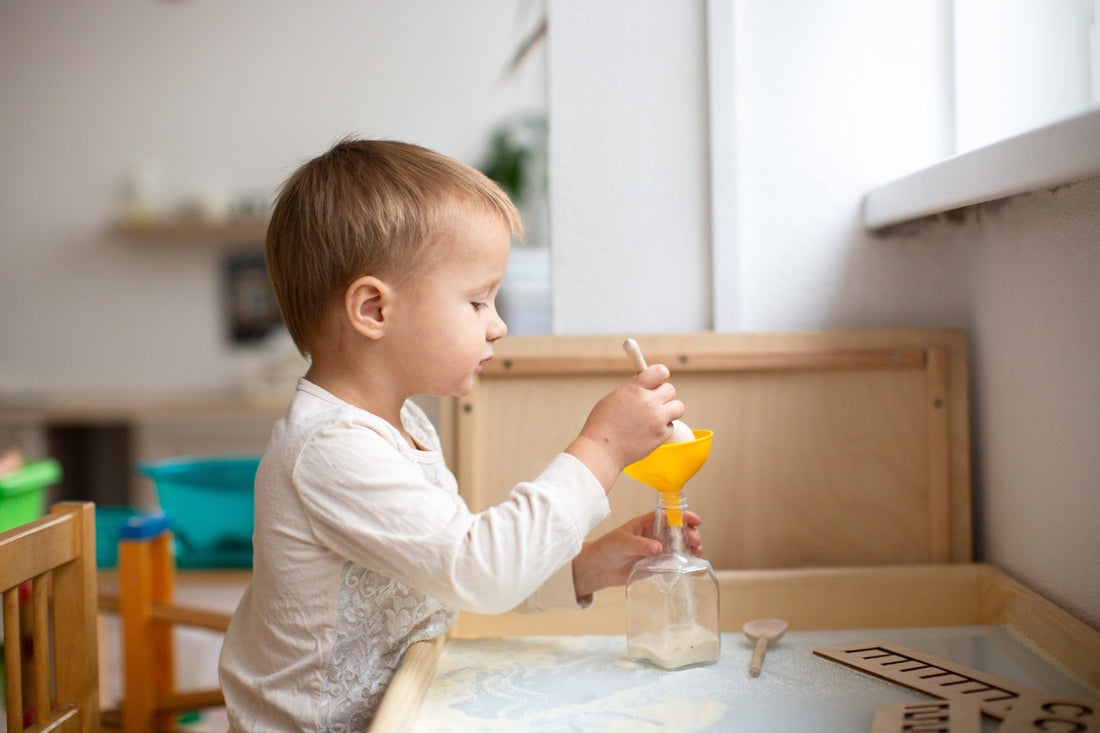 A toddler does a pouring fine-motor activity.