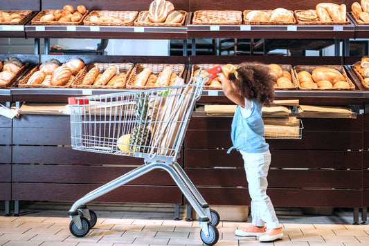 A toddler pushes a shopping cart in the bread aisle