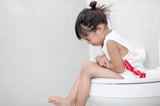 A toddler sits on the toilet refusing to poop