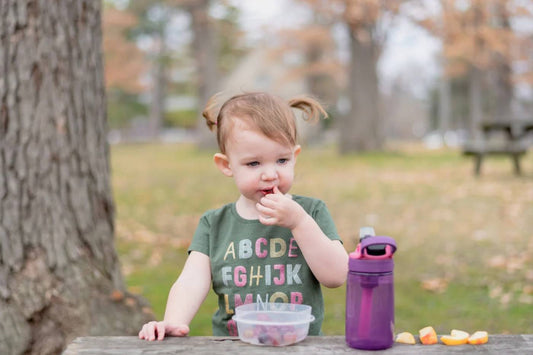 nappy bag snacks: toddler eating snacks in park