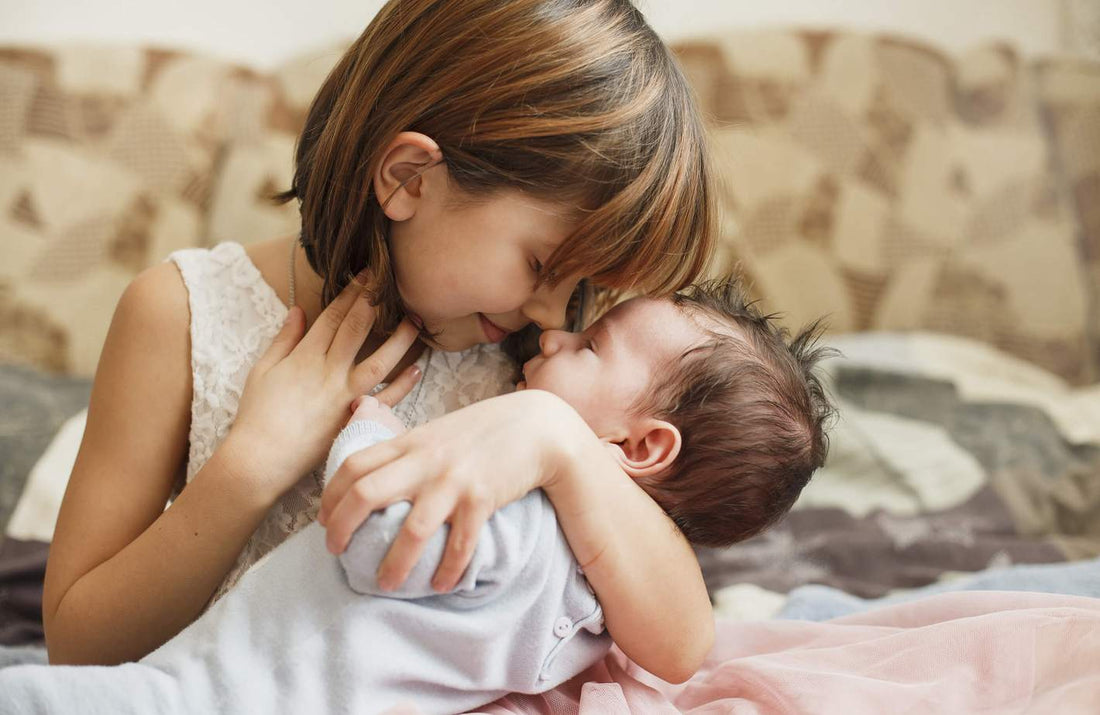 older-sister-holding-her-new-baby-brother