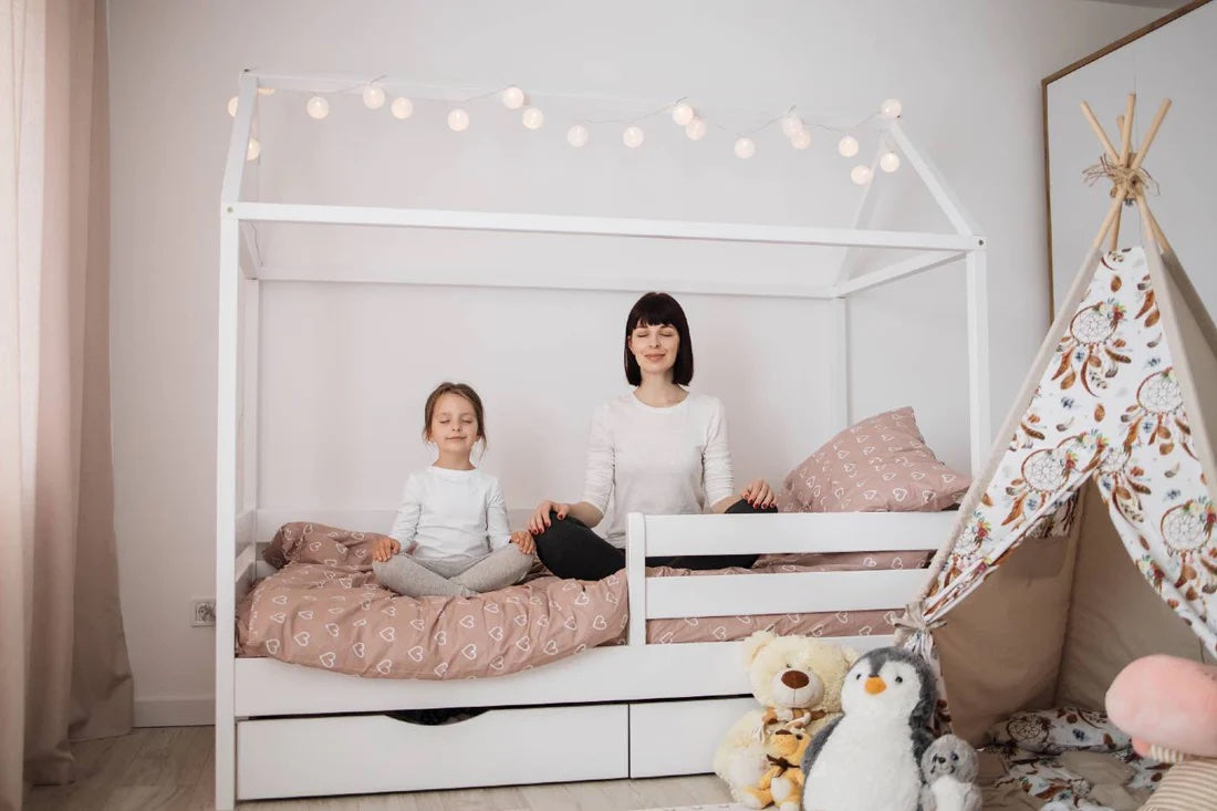 Mum and daughter meditate together on a child's bed